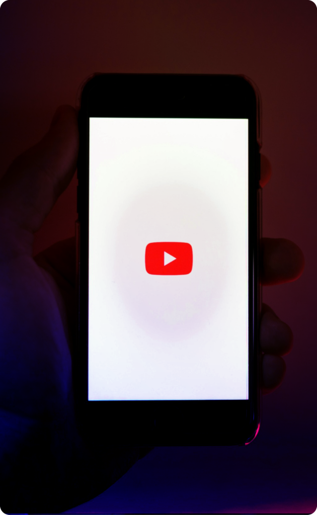 A hand holding a phone with the youtube logo inside