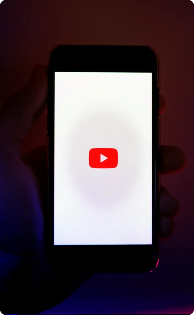 A hand holding a phone with the youtube logo inside